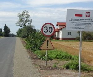Droga gminna po przebudowie, po prawej stronie znak ograniczający prędkość oraz tablica informacyjna 