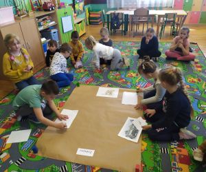 Dzieci naklejają obrazki na szary papier