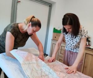 Osoby wykrajają ubrania ze wzornika podczas warsztatów z szycia ubrań w stylu BOHO.