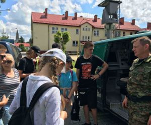 Grupa młodzieży słucha pracownika straży granicznej.