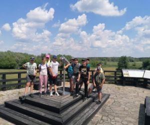 Uczniowie znajdują się wraz z nauczycielem na wzgórzu, w punkcie widokowym