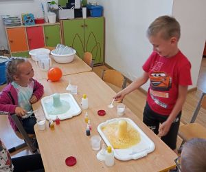 Dwie dziewczynki i dwóch chłopców prezentują swoje kolorowe wulkany.