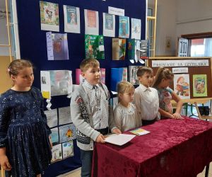 Uczniowie stoją na tle gazetki przygotowanej z okazji pasowania na czytelnika