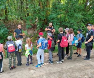 Grupa dzieci wraz z instruktorami podczas zajęć z survivalu, na świeżym powietrzu.
