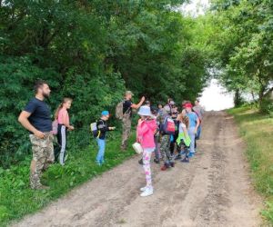 Grupa dzieci wraz z instruktorami podczas zajęć z survivalu, na świeżym powietrzu.