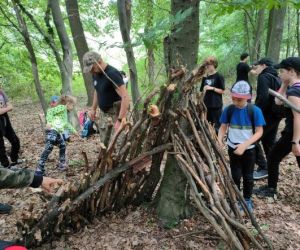 Grupa dzieci wraz z instruktorami podczas zajęć z survivalu, na świeżym powietrzu.