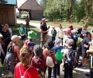 Grupa dzieci wraz z instruktorami podczas zajęć z survivalu, na świeżym powietrzu.