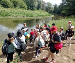 Grupa dzieci wraz z instruktorami podczas zajęć z survivalu, na świeżym powietrzu.
