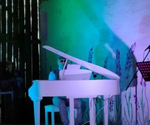 Osoba gra na fortepianie wewnątrz budynku.