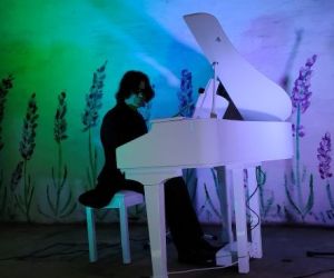 Osoba gra na fortepianie wewnątrz budynku.