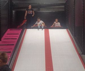 Zdjęcie przedstawia dzieci bawiące się na zjeżdżalni w Parku Trampolin.