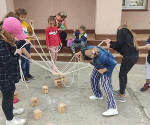 Zdjęcie przedstawia dzieci bawiące się zabawką animacyjna na zewnątrz budynku.