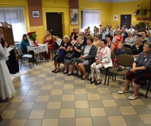 Na zdjęciu widoczna jest grupa osób siedząca wewnątrz budynku.