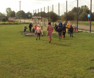 Dzieci pod opieką nauczycielki zbierają śmieci.