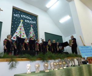 Kobiety stojące na scenie. Przed nimi mikrofony. Przed ni mi mężczyzna z akordeonem. 