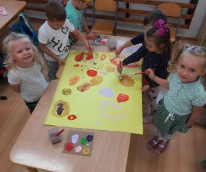 Przedszkolaki malują farbami plakat w kolorowe kropki
