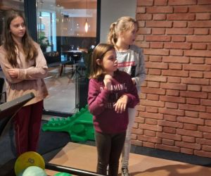 Trzy dziewczynki szykują się do gry w kręgle, czekają aż zapali się zielone światełko