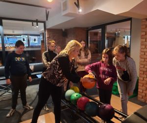 Nauczycielka pomaga uczennicom wybrać kulę do gry w kręgle