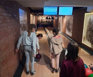 Uczennica rzuca kulą, koleżanki stoją obok i jej kibicują