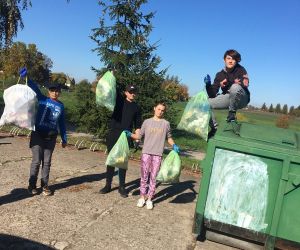 Uczniowie klasy VIII wrzucają śmieci do kontenera przy szkole