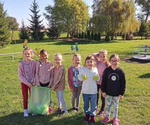 Uczniowie klasy I z workami śmieci zebranymi na terenie wokół szkoły