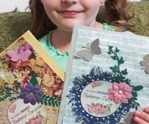 Dziewczynka trzymająca własnoręcznie wykonane kartki dla babci i dziadka.