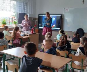 Zdjęcie przedstawia uczniów klas I-III siedzących w ławkach i słuchających prelekcji