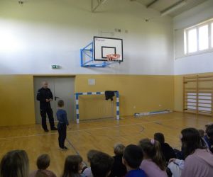 Policjant i chętny uczeń demonstrują bezpieczne przechodzenie przez jezdnię