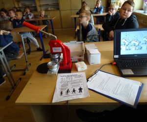 Dzieci razem z osobą prowadzącą zajęcia, w klasie.