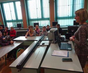 Dzieci razem z osobą prowadzącą zajęcia, w klasie.