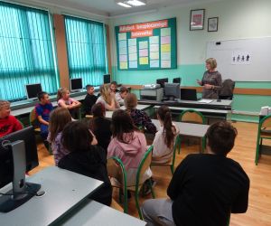 Dzieci razem z osobą prowadzącą zajęcia, w klasie.