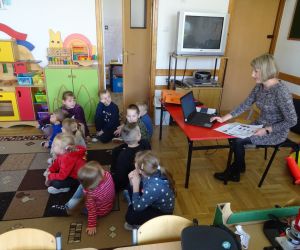 Dzieci razem z osobą prowadzącą zajęcia, w klasie.