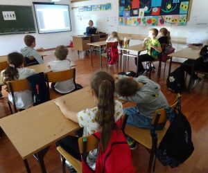 Dzieci razem z osobą prowadzącą zajęcia, w klasie.