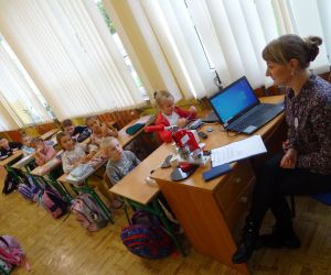 Dzieci razem z osobą prowadzącą zajęcia, w klasie.