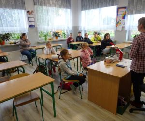 Dzieci razem z osobą prowadzącą zajęcia, w klasie.