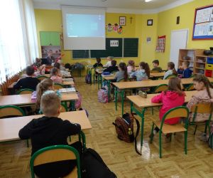 Dzieci razem z osobą prowadzącą zajęcia, w klasie.