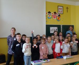 Dzieci razem z osobą prowadzącą zajęcia, w klasie.