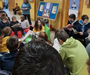 Uczniowie czytają książki na szkolnym korytarzu , pilnuje ich nauczycielka