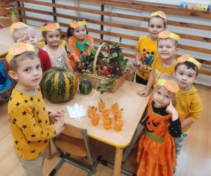 Przedszkolaki przy stoliku z dyniami i szklankami z sokiem dyniowym