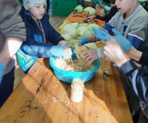 Uczniowie klasy IV mieszają kapustę z tartą marchewką