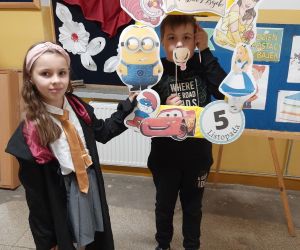 Dziewczynka w stroju Małej Czarodziejki z Harrego Pottera trzyma ramkę chłopcu w masce kucyka