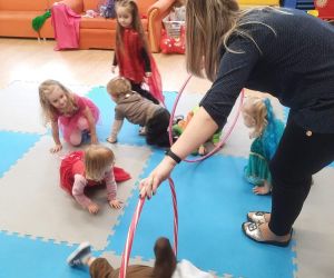 Przedszkolaki przebrane za postacie z bajek na torze przeszkód trzymanym przez nauczycielkę