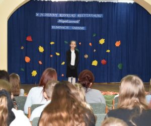 Zdjęcie przedstawia dziecko występujące na scenie. widoczna jest również publiczność oglądająca.