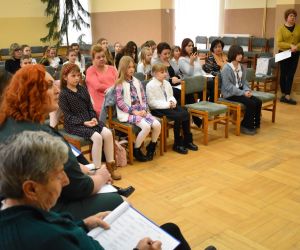Zdjęcie przedstawia publiczność zgromadzona w budynku, słuchającą występujących recytatorów.