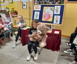 Dziewczynka z misiem na kolanach czyta opowieści o misiu