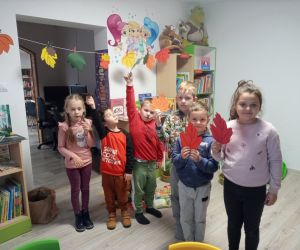 Na zdjęciu widoczne są dzieci pozujące do zdjęcia z papierowymi liśćmi.