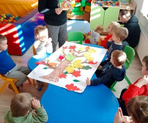 Na zdjęciu widoczne są małe dzieci siedzące przy stoliku.