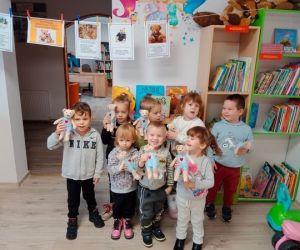 Na zdjęciu widoczna jest grupa małych dzieci trzymających w dłoniach przytulanki.