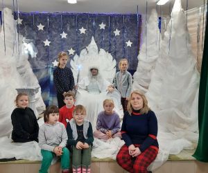 Nauczycielka z uczniami na wspólnym zdjęciu z królową śniegu siedzącą na tronie