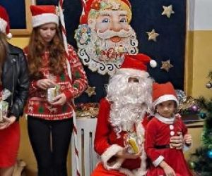 Dziewczynka na wspólnym zdjęciu z Mikołajem i pomocnikami Mikołaja